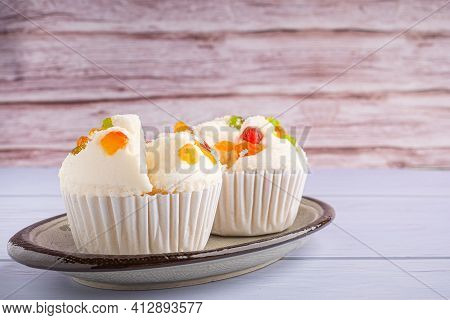 Side View Of Thai Steamed Cupcakes Topped With Dry Fruit On Plate On Blue Cloth With Wooden Backgrou