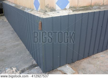 An Outside Old Brick Foundation Is Covered With Metal Siding, Steel Siding To Protect The Foundation