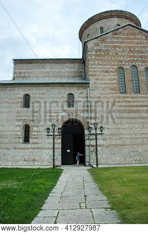 Th Road Leads To The Gate Of An Ancient Medieval Temple. The Figure Of A Girl Stands Near The Gate. 