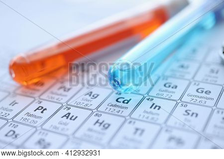 Two Test Tubes With Colored Reagents Lying On Periodic Table Closeup