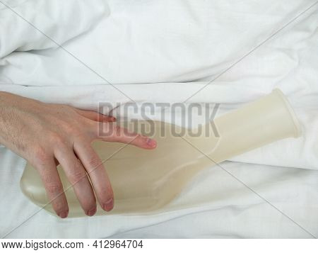 Male hand holds urinal pot in the hospital. Lying patient after surgery in a hospital bed. Medical theme. Medical equipment for patients in Ukrainian hospital.