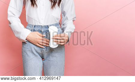 Studio Shot Of A Young Girl Feeling The Pain Of Menstruation With A Pantyliner In Her Hands. Space F