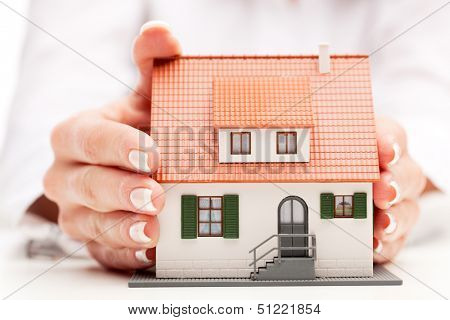 pisture of man and woman hands holding paper house