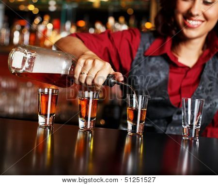 Beautiful redhead barmaid making shots
