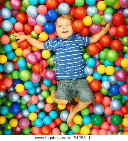Happy child playing at colorful plastic balls playground high view