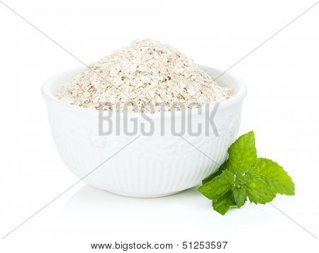Oat flakes in bowl and mint. Isolated on white background
