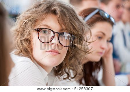 Cute schoolgirl with glasses posing in a schoolroom