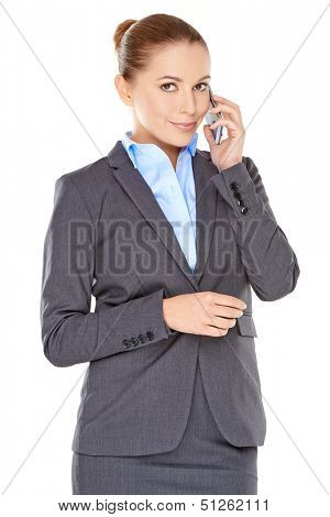 Stylish young businesswoman on her mobile phone standing listening to the conversation with a feint smile