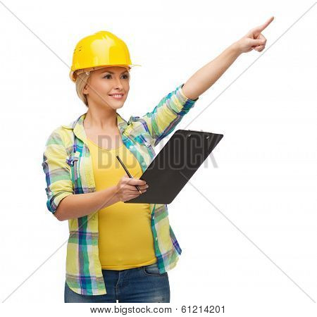 repair, construction and maintenance concept - smiling woman in helmet with clipboard pointing finger