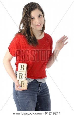 A pretty young teen happily waving as she hold rustic alphabet blocks with the letters she uses on her phone:  BRB, standing for 