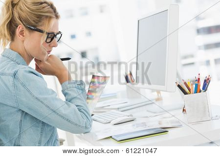 Blonde focused designer working at her desk in creative office