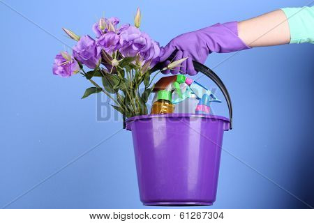 Housewife holding bucket with cleaning equipment on bright background. Conceptual photo of spring cleaning. 