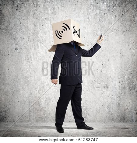 Businessman using mobile phone wearing carton box on head