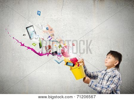 Young boy splashing colorful paint from bucket