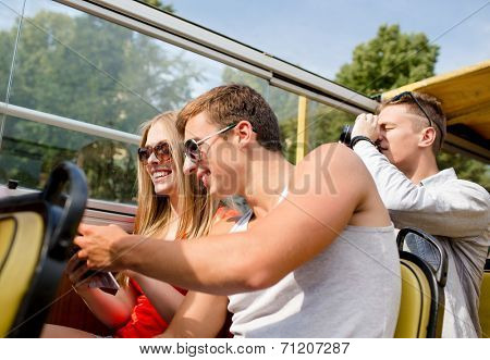 friendship, travel, vacation, summer and people concept - smiling couple looking to city guide book traveling by tour bus