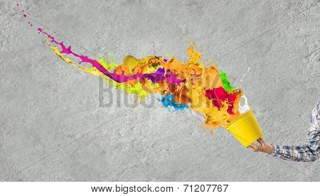 Close up of hand splashing colorful paint from bucket