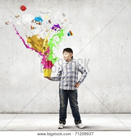 Young boy splashing colorful paint from bucket
