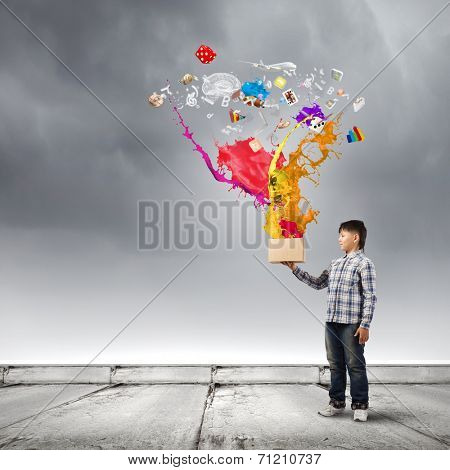 Young boy splashing colorful paint from bucket