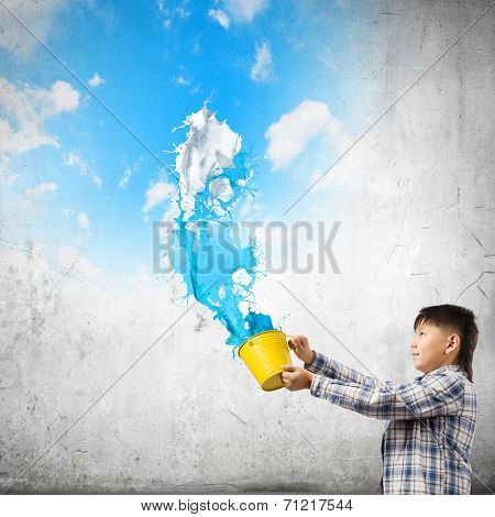 Young boy splashing colorful paint from bucket