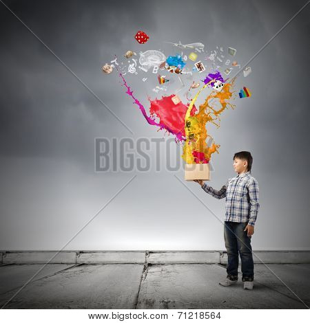 Young boy splashing colorful paint from bucket