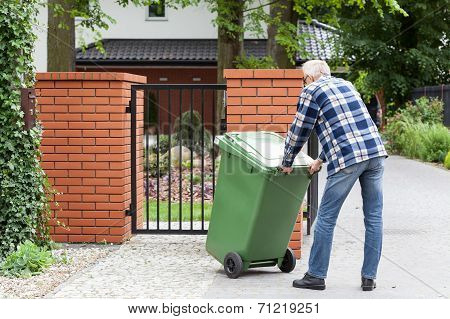 Man Is Pushing Wheeled Dumpster