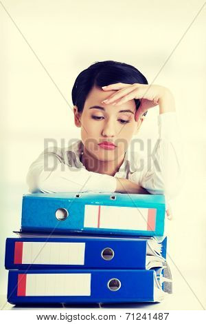 Sad woman with ringbinders sitting at the desk. Tired and exhousted business woman.