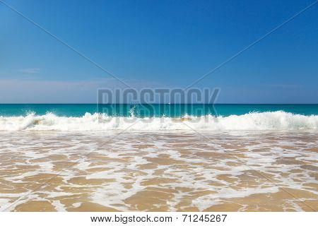 Waves crashing on beautiful sandy beach on sunny day in Sri Lanka.