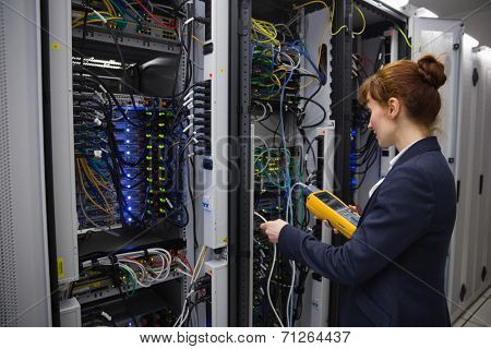 Happy technician using digital cable analyzer on server in large data center