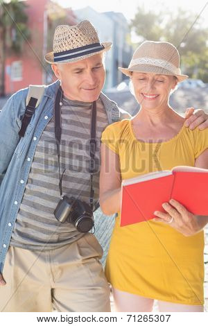 Happy tourist couple using guide book in the city on a sunny day