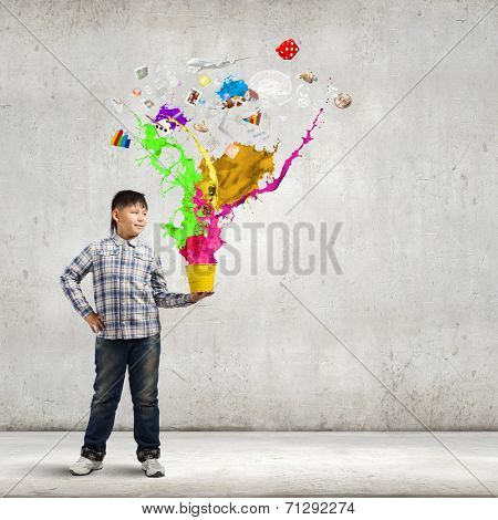 Young boy splashing colorful paint from bucket