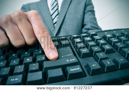 closeup of a businessman pressing the inter key of a computer keyboard