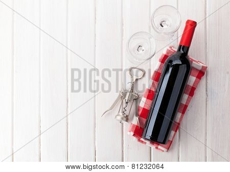 Red wine bottle, glasses and corkscrew on white wooden table background with copy space