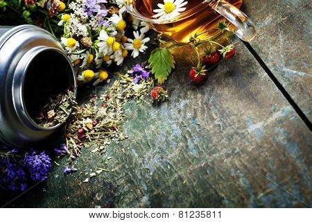 Herbal tea and wild organic flowers on wooden background