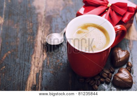 Valentine's day composition with coffee cup and chocolate on wooden background