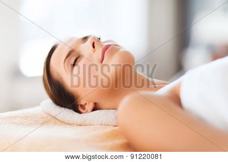 beauty and spa concept - beautiful woman in spa salon lying on the massage desk
