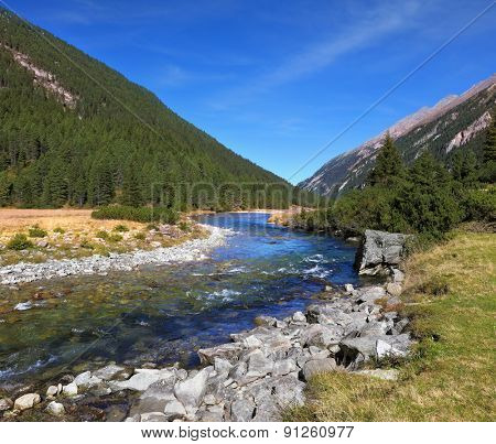 National park Krimml falls in Austria. Idyllic landscape. Upper courses of falls - rather narrow fast seething small river among green mountain meadows