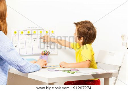 Boy points at activities on calendar learning days
