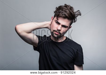 Young handsome man doubting on gray background