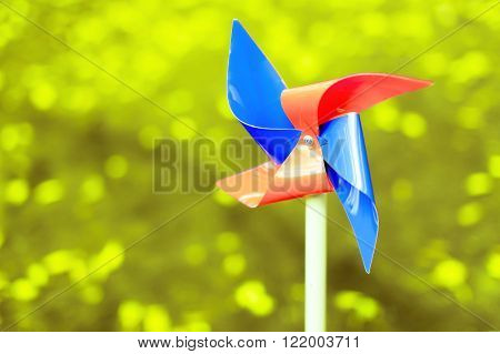 red and blue pinwheel. no wind conditions.motionless colorful pinwheel of four wings on a green blur background. copy space for your text