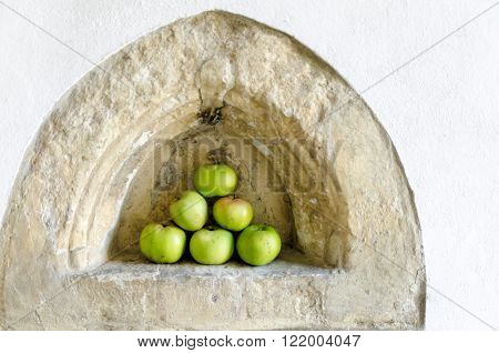 Apples piled in a triangle shap in a medieval alcove