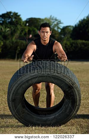 sportman flipping huge tire on grass stadium