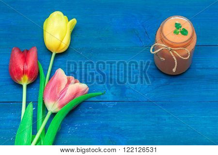 glass of fruit smoothie decorated with mint leaves and lie next to tulips