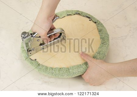 upholstering a padded part of soft chair by staple gun with textile covering