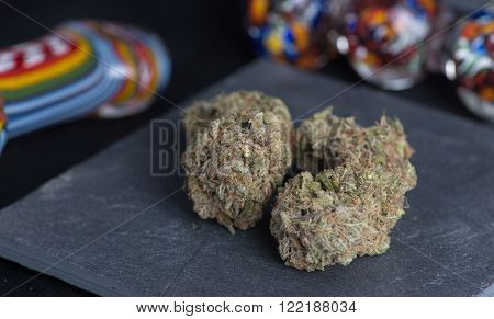 Granddaddy Purple medicinal medical marijuana on a piece of slate surrounded by some color.