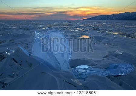 Transparent icicles at sunset. Beautiful winter landscape in the Lake Baikal.