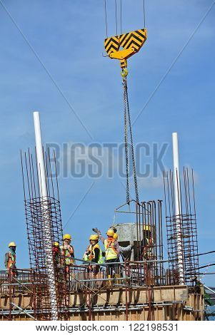 SELANGOR, MALAYSIA -NOVEMBER 21, 2015: A group of construction workers pouring concrete using concrete bucket into the beam form work at the construction site.