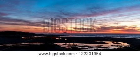 Hokio beach at sunset with the river flow to the sea.