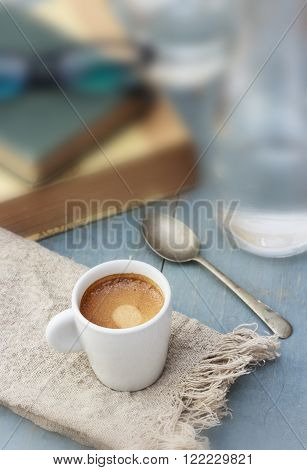 Espresso with water on blue wooden table, with books in the background
** Note: Shallow depth of field