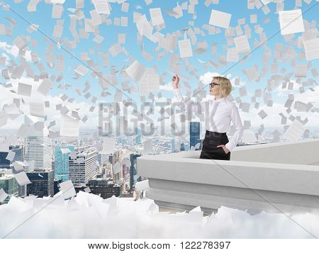 Businesswoman standing on roof throwing paper plane Paris view papers flying around. Blue sky at background. Concept of starting new project.