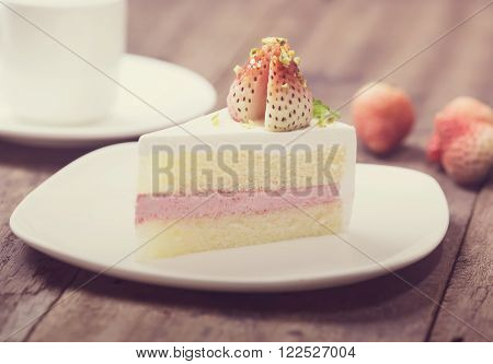 close up of strawberry cream cake on white on the wood background, vintage toning